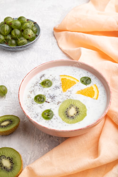 Preview: Yogurt with kiwi, gooseberry, chia in ceramic bowl on gray concrete background. Side view.