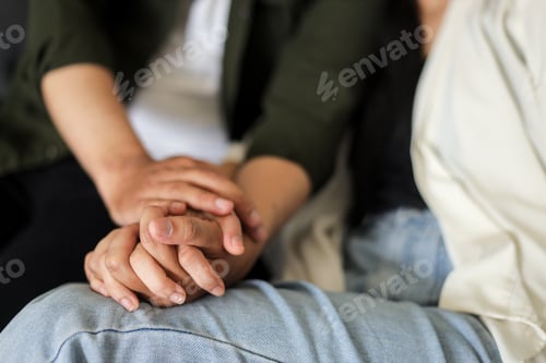 Preview: Close up of woman and man in love sitting on couch while holding hands.