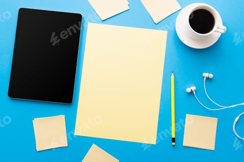 Preview: top view of digital tablet with blank screen near cup of coffee and empty papers on blue