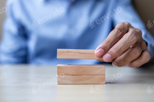 Preview: hand holding wooden building blocks on table background