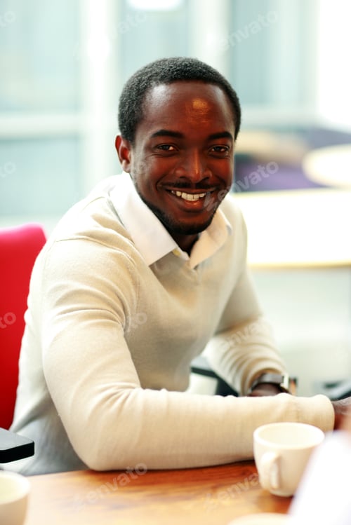Preview: Happy African Businessman Sitting At The Table In Office