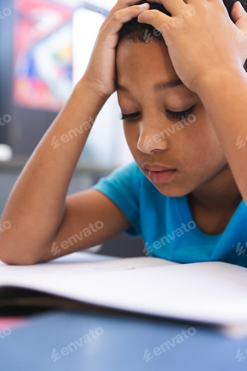 Preview: Biracial boy studies intently in the classroom at school