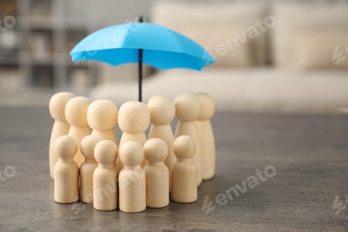 Preview: Human figures under umbrella on grey table indoors, space for text. Insurance concept