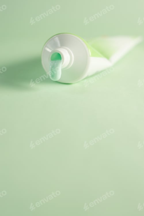 Preview: Dripping mint toothpaste tube isolated on green background - the concept of oral health