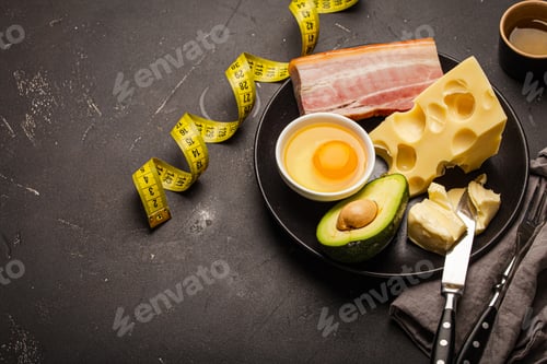 Preview: Foods for keto diet on black plate, measure tape on dark background
