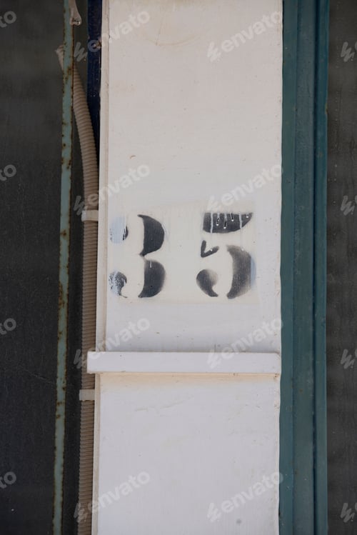 Preview: Vertical shot of a painted house number '35' on a pillar