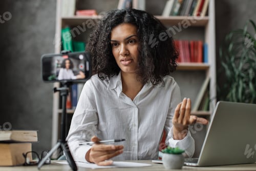 Preview: Beautiful young woman in white shirt talking with subscribers while writing report and gestures