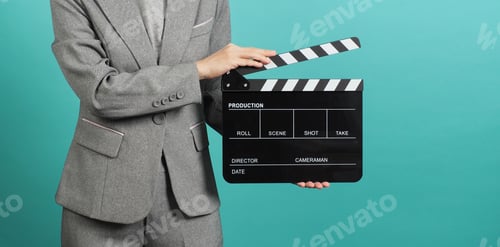 Preview: Woman hands holding black Clapper board and wear grey suit on green or Tiffany Blue background.