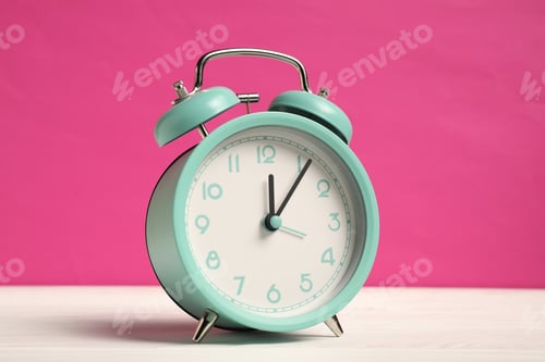 Preview: One turquoise alarm clock on white wooden table against bright pink background
