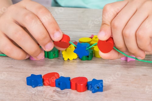 Preview: Preschooler making bracelet from thread and colored beads