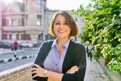 Preview: Outdoor portrait of smiling mature business woman with crossed arms