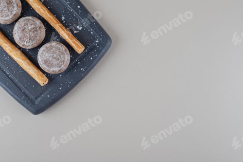 Preview: Small cookies and stick crackers on navy platter on marble background