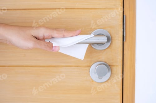 Preview: hand cleaning doorknob by wet wipes against coronavirus or Corona Virus Disease (Covid-19)