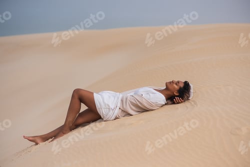 Preview: Woman laying on sand dune and sunbathing