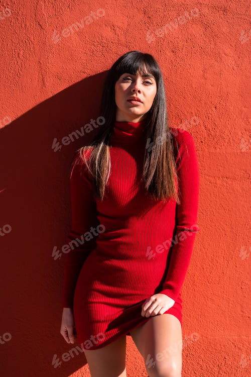 Preview: Posed brunette girl in a dress in spring. Caucasian pretty a red background