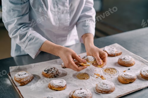 Preview: beautiful woman baker tears ready freshly baked hot aromatic buns and checks dough bakery production
