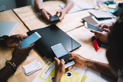 Preview: Multiethnic colleagues using smartphones on meeting in office