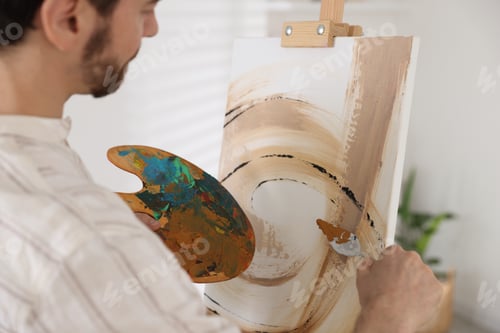 Preview: Man painting picture on easel in artist's studio, closeup
