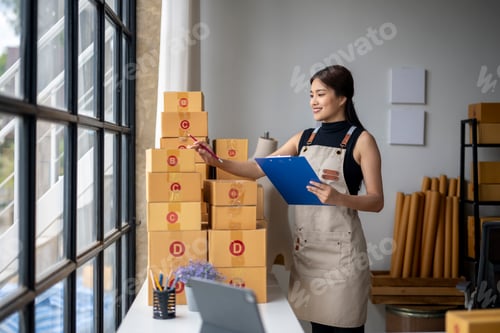 Preview: A woman is standing in front of a stack of boxes and writing on a clipboard