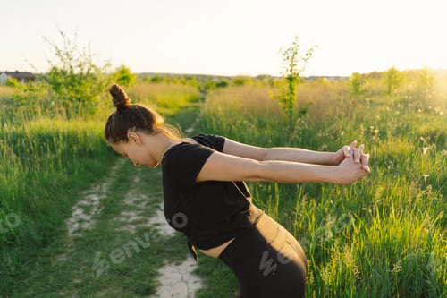 Preview: Beautiful girl doing fitness or yoga in nature on a sunny summer sunset.