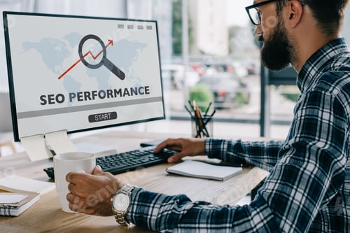 Preview: young successful developer working with computer with"SEO performance" on screen at workplace