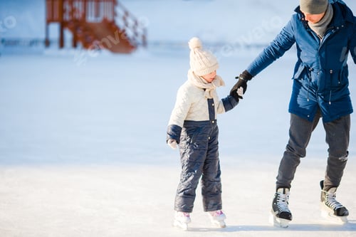 Preview: Young father and adorable little girl have fun on skating rink outdoors