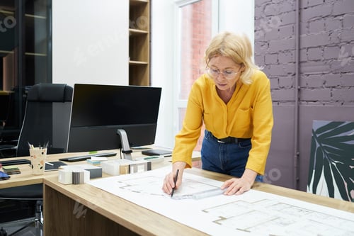 Preview: Female architect drawing blueprint at office