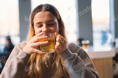 Preview: Portrait of a joyful teengirl enjoying a cup of tea at cafe