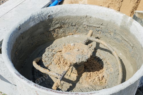 Preview: Cement mixer with gray mortar and tan sand churning inside. Blades partially visible, stirri