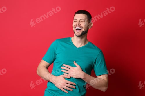 Preview: Handsome man laughing on red background. Funny joke