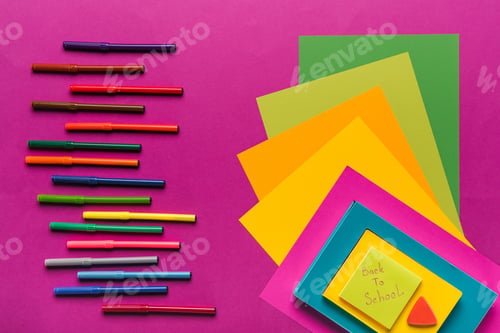 Preview: composition of colorful papers and markers in row on purple