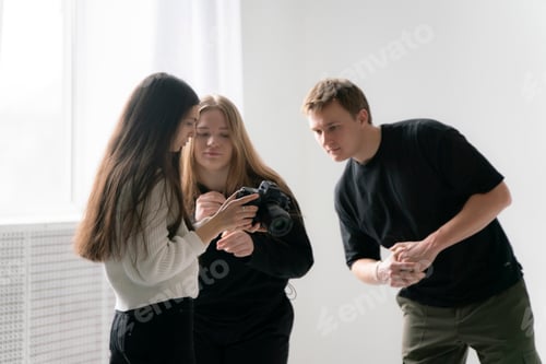 Preview: Young Photographer Demonstrates Camera Results to Two clients in Bright Indoor Setting