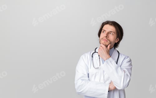 Preview: Pensive Young Doctor Touching Chin And Looking At Copy Space