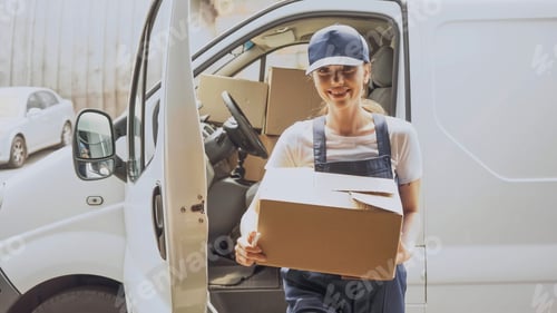 Preview: Smiling delivery woman holding carton box near car outdoors