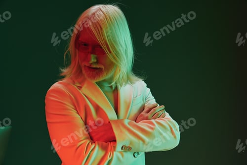 Preview: Man with long white hair in a stylish suit, illuminated with vibrant green and red lighting