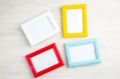 Preview: Overhead view of four empty picture frames in different colours on stripped background