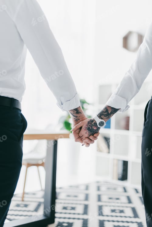 Preview: partial back view of couple in formal wear holding hands in office