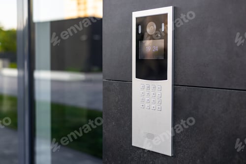 Preview: Entrance doorbell in a multi-apartment building, with a video surveillance camera, on a dark wall