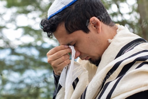 Preview: A Jew performs a religious prayer ritual by holding the Tzitzit to his eyes while praying to his god