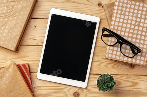 Preview: Top view of wooden table with white digital tablet with black screen on it