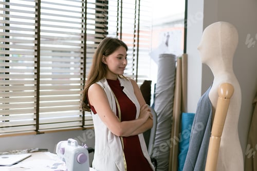 Preview: Young fashion designer woman watching dress on mannequin