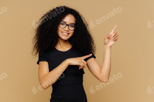 Preview: Isolated shot of happy African American woman points up and aside