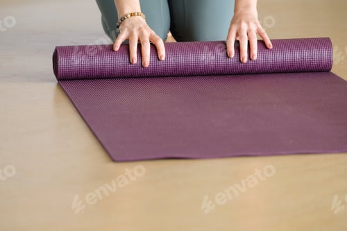 Preview: Woman Rolling Up Yoga Mat for Exercise