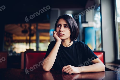 Preview: Pensive woman sitting at table in cafe
