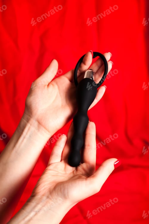 Preview: Female Hands Holding Adult Novelty Toy Against Red Fabric