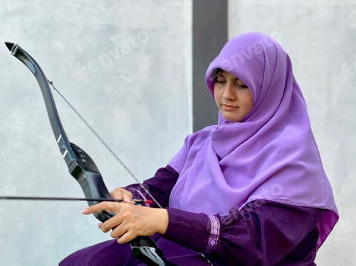 Preview: Hijab young woman sitting and preparing archery set
