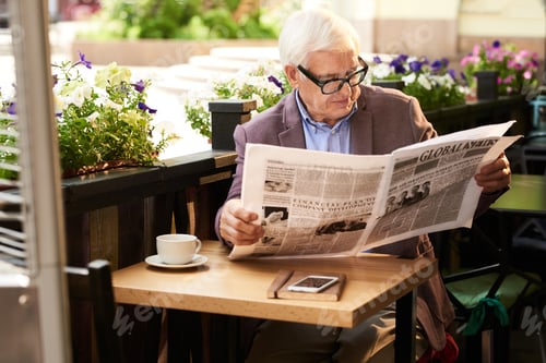 Preview: Modern Senior Man Reading Newspaper Outdoors