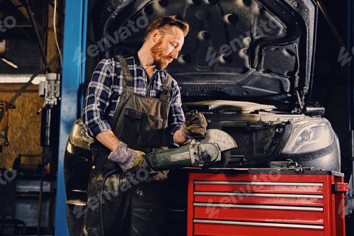 Preview: Mechanic cuts steel car part with an angle grinder.