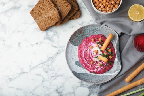 Preview: Flat lay composition with plate of tasty beet hummus and bread on marble table