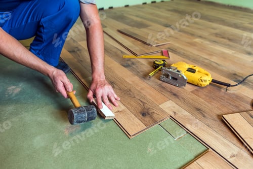Man Installing Wood Flooring with Tools